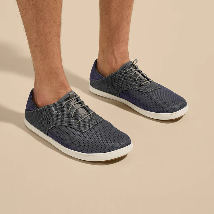 Navy blue sneakers with white soles worn by a person on a beige background