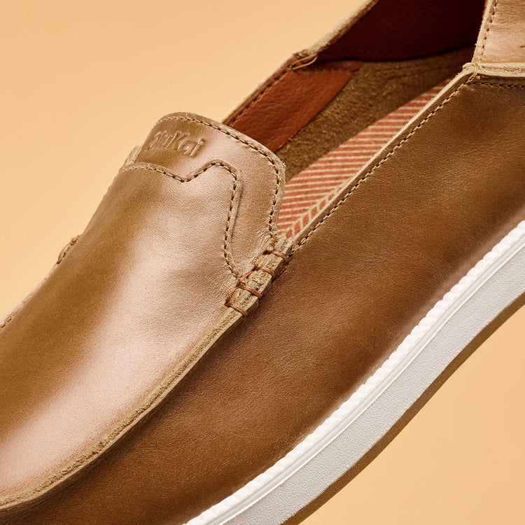 Brown leather shoe with white sole on a beige background