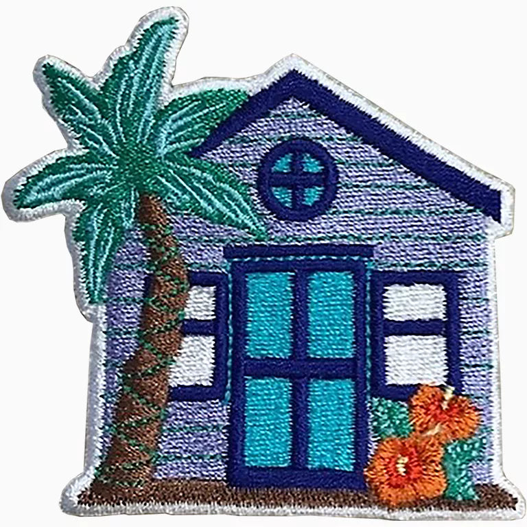 Embroidered patch of a beach house with palm tree and flowers on a white background