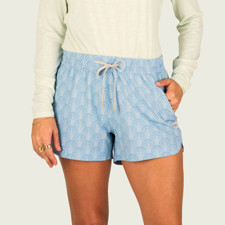 Person wearing light blue patterned shorts with a white background
