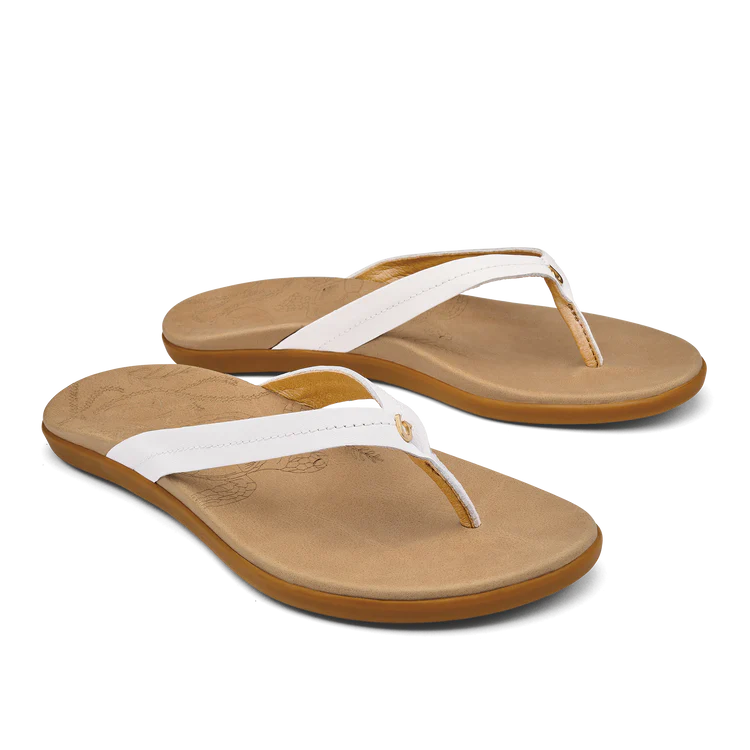 Pair of tan sandals with white straps on a white background