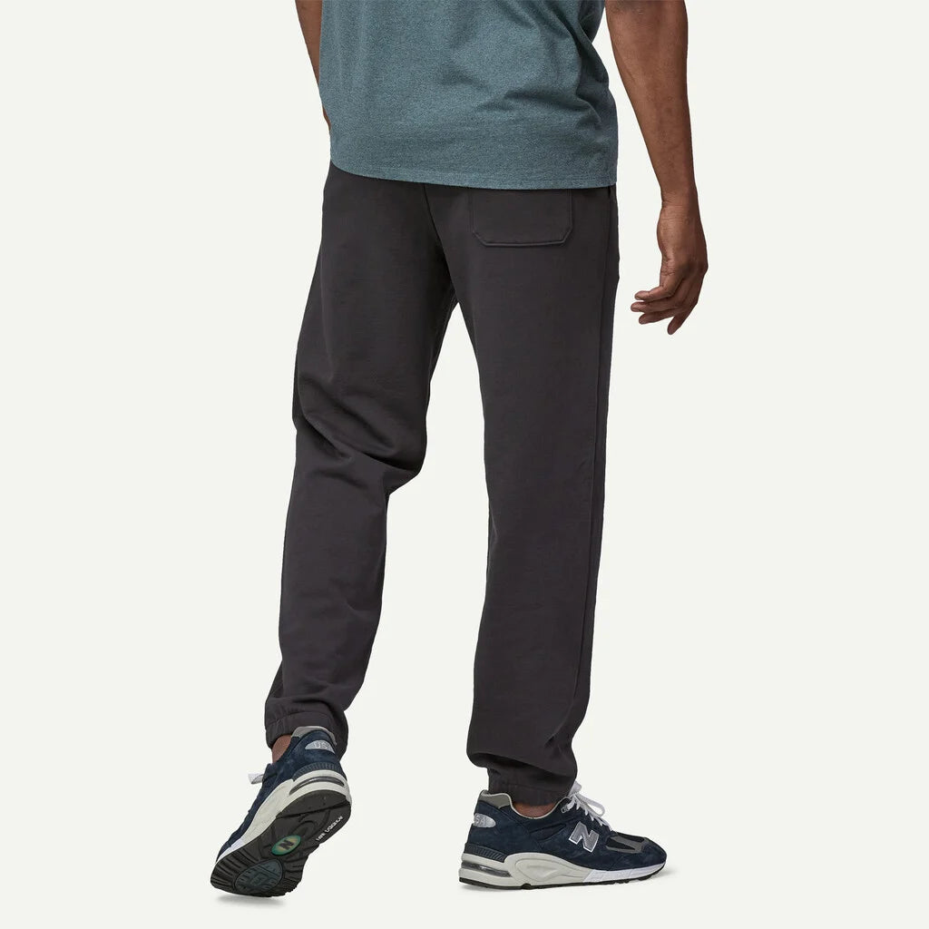 Person wearing dark gray jogger pants and blue sneakers on a white background