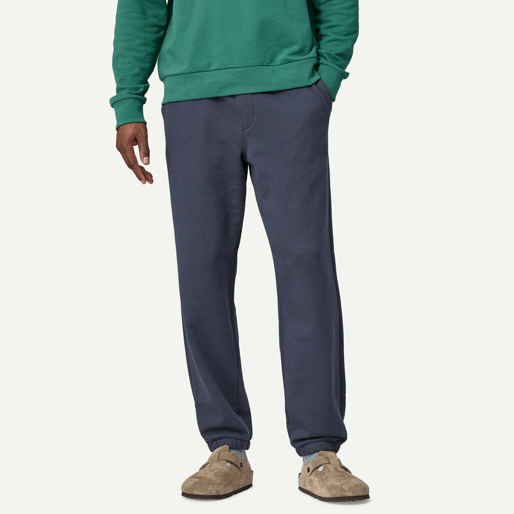 Person wearing a green sweatshirt and navy pants on a white background