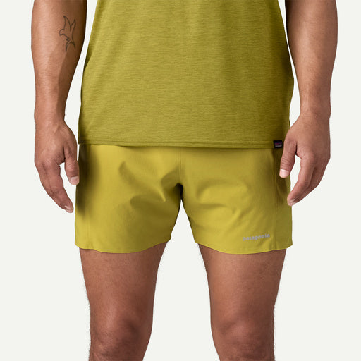 Person wearing a green tank top and shorts on a plain background