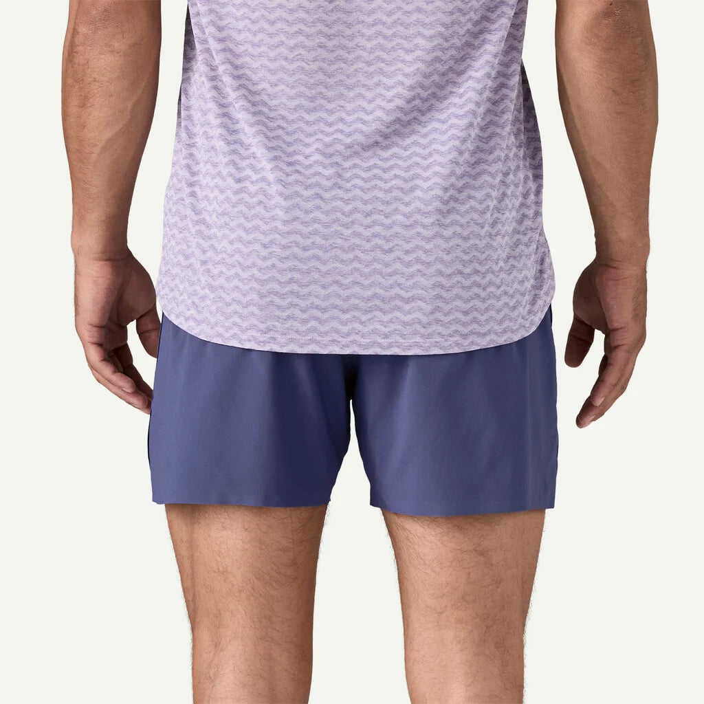 Person wearing a light purple athletic shirt and blue shorts on a white background