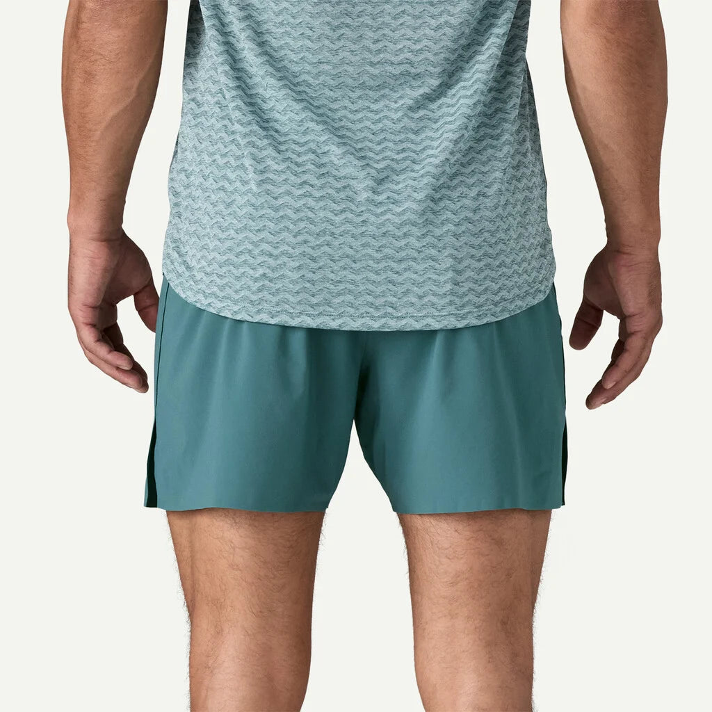 Person wearing a light blue athletic shirt and teal shorts on a white background