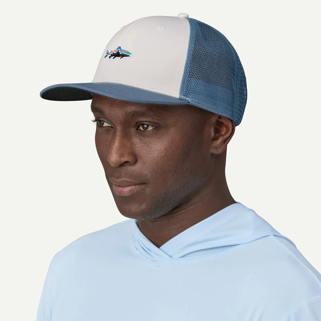 Man wearing a blue and white cap with a logo on a light gray background