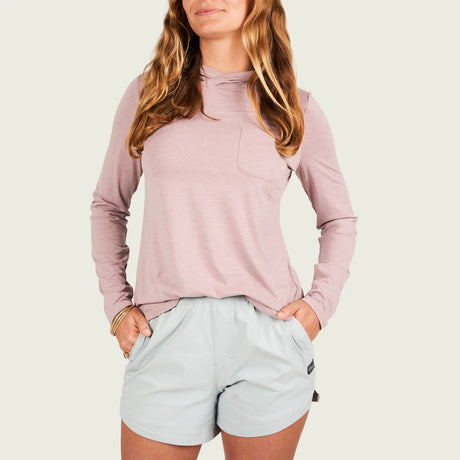 Woman wearing a light pink long-sleeve top and light gray shorts on a white background