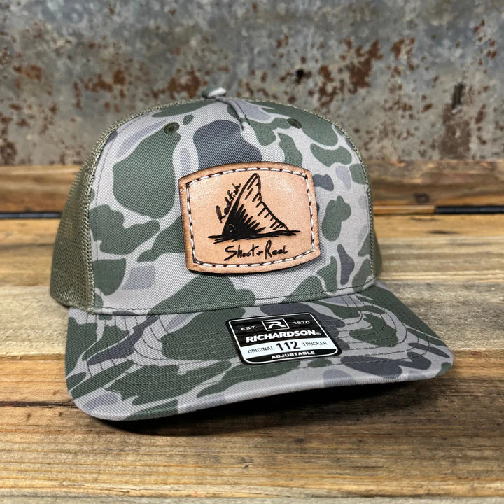 Camouflage trucker hat with leather patch on a wooden surface