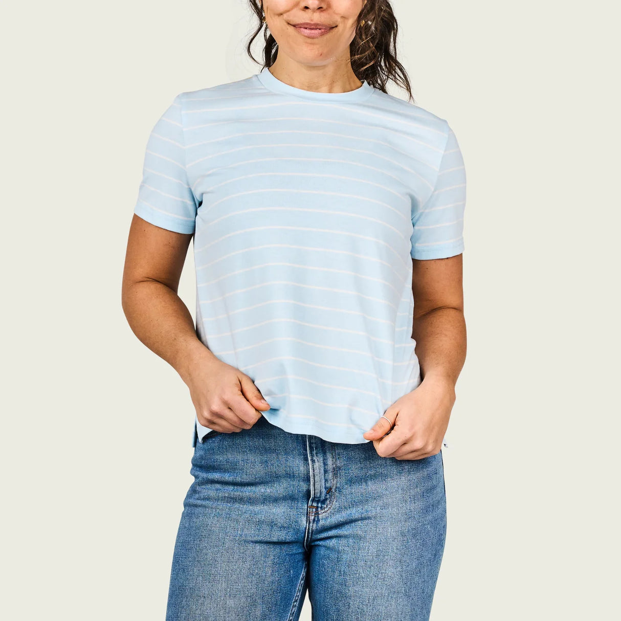 Person wearing a light blue striped t-shirt and jeans on a plain background