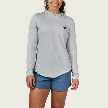 Woman wearing a gray long-sleeve athletic hoodie and blue shorts on a white background