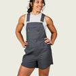 Woman wearing gray overalls on a plain background