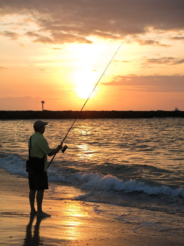 man surf fishing at sunset