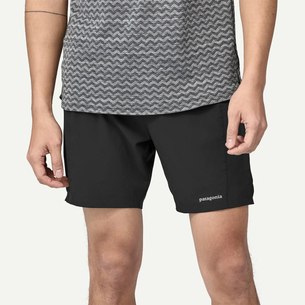 Person wearing black shorts with Patagonia logo on a white background