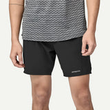 Person wearing black shorts with Patagonia logo on a white background
