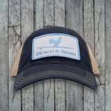 Black and beige cap with 'Beach & Barn' logo on a wooden background