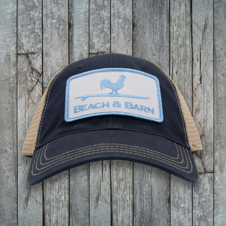 Black and beige cap with 'Beach & Barn' logo on a wooden background